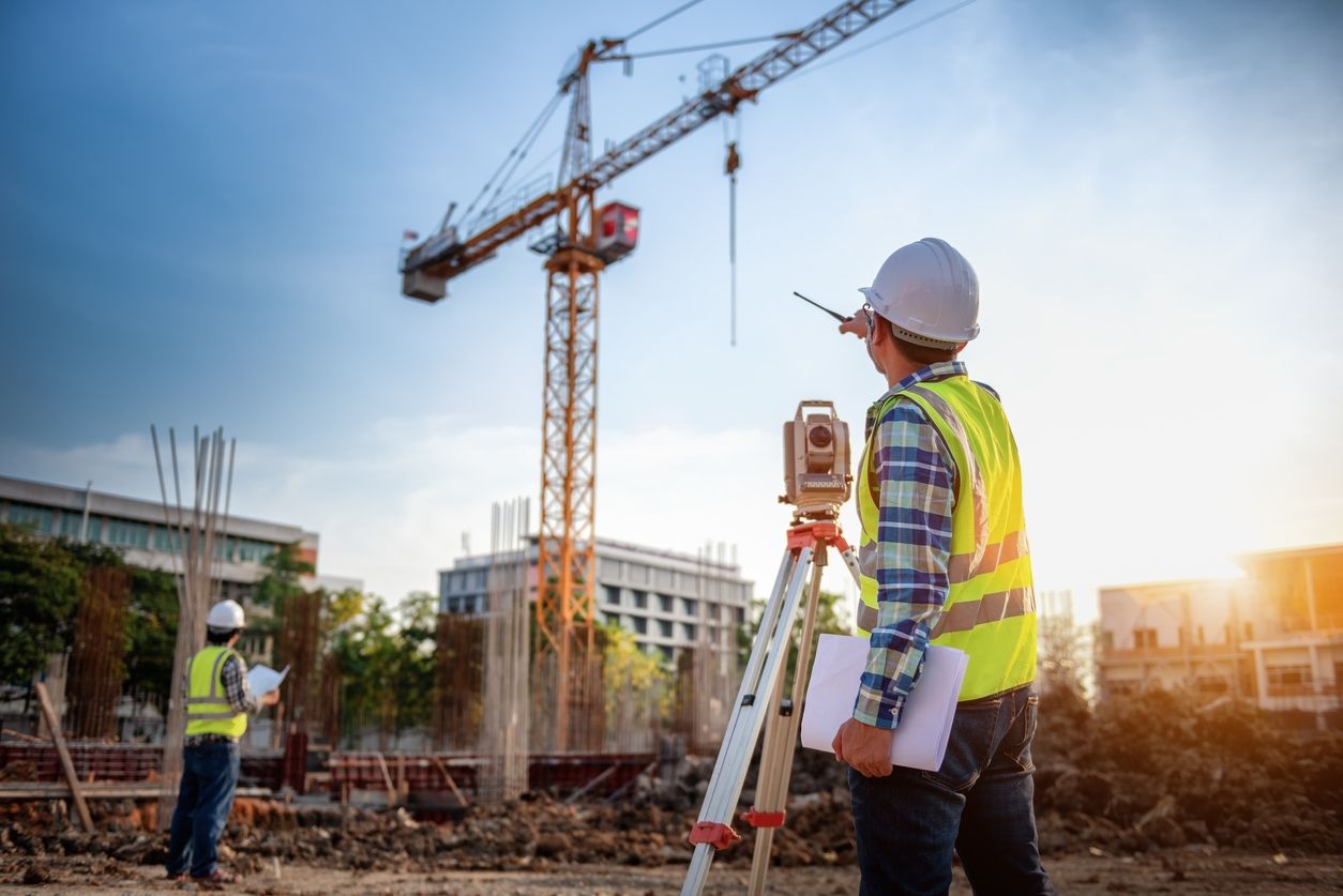 Zwei Bauarbeiter stehen mit Warnweste und Bauhelm auf einer Baustelle