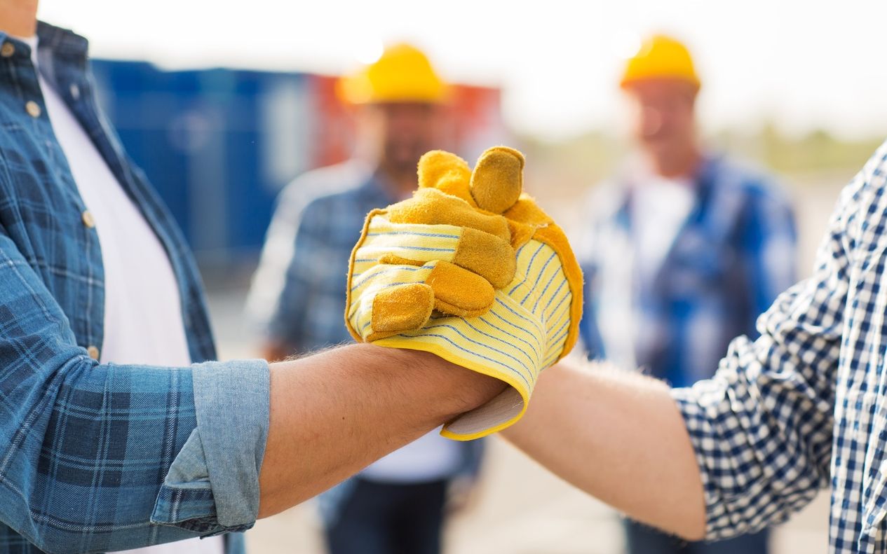 Zwei Handwerker mit Bauhandschuhen geben sich die Hand